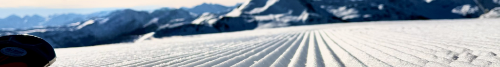 Frisch präparierte Skipiste mit klaren Linien vor Berglandschaft