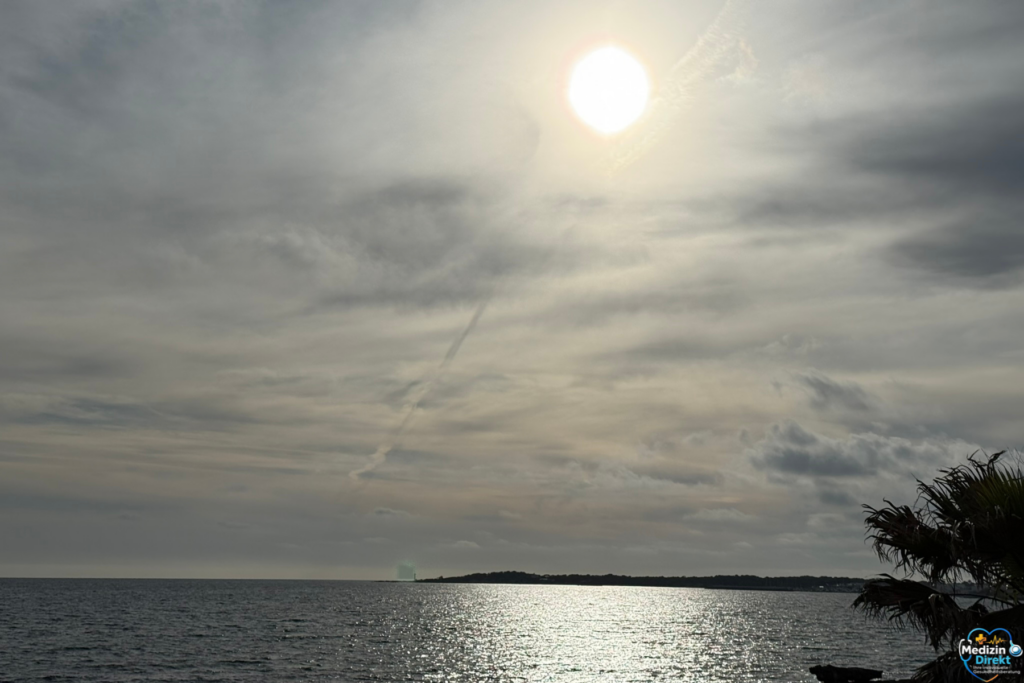 Sonne über dem Meer mit ruhiger Wasseroberfläche und hellem Himmel